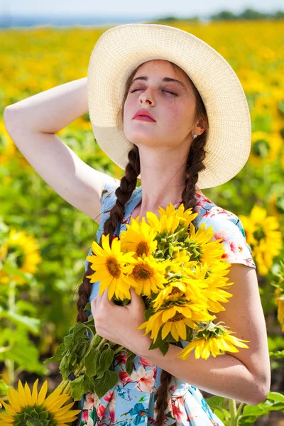 Porträtt av en ung vacker flicka i ett fält av solrosor — Stockfoto