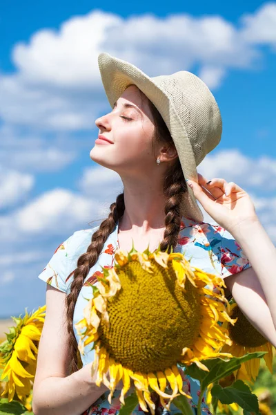 Porträtt av en ung vacker flicka i ett fält av solrosor — Stockfoto