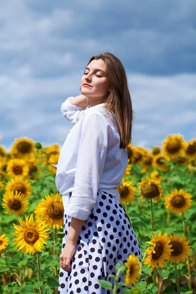 Porträtt av en ung vacker flicka i ett fält av solrosor — Stockfoto