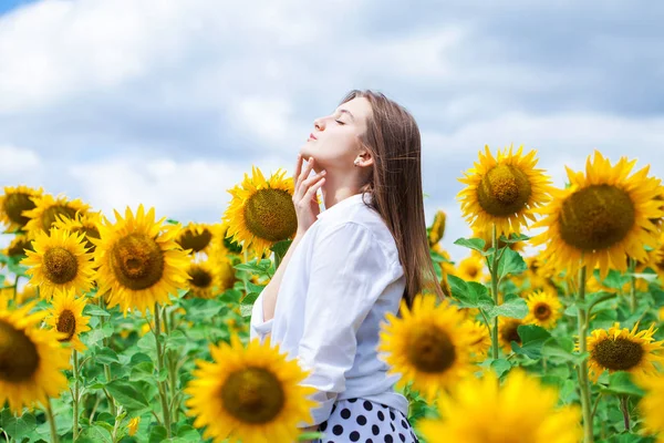 Porträtt av en ung vacker flicka i ett fält av solrosor — Stockfoto