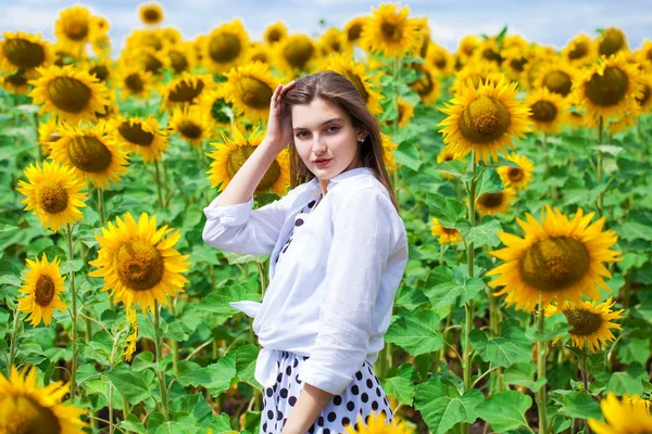 Retrato de una joven hermosa en un campo de girasoles — Foto de Stock