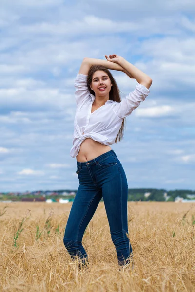 Mladá brunetka v bílé košili a modré džíny — Stock fotografie