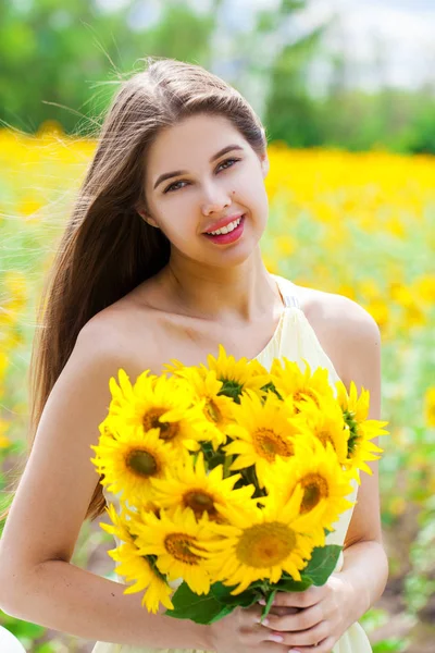 Jonge mooie vrouw met een boeket bloemen in een veld van Su — Stockfoto