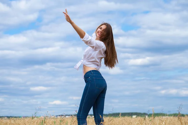 Jonge brunette vrouw in wit overhemd en blauwe jeans — Stockfoto