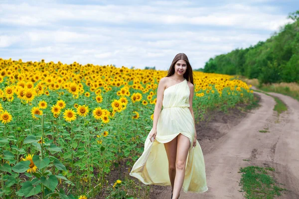 Porträtt av en ung vacker flicka i ett fält av solrosor — Stockfoto