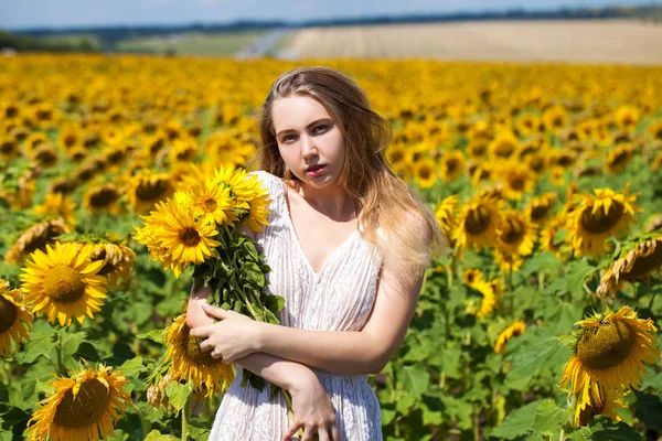 Unga vackra kvinnan i ett fält av solrosor — Stockfoto
