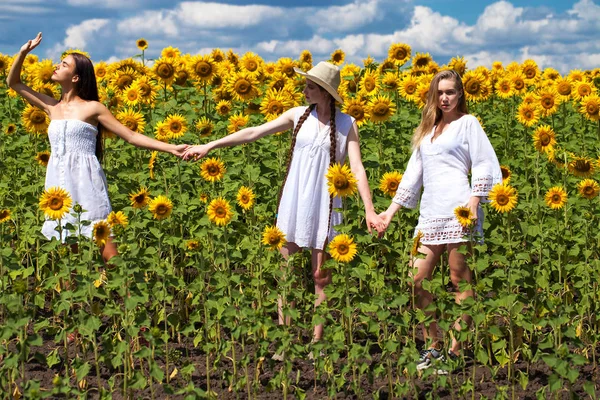 Três jovens mulheres de vestido branco posando contra o céu azul em — Fotografia de Stock
