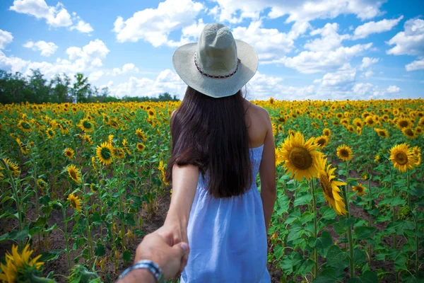 Siga-me, jovem segurando um cara mão um campo de girassóis — Fotografia de Stock