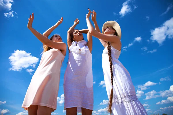 Três jovens mulheres de vestido branco posando contra o céu azul em — Fotografia de Stock