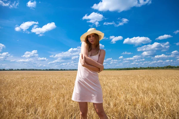 Menina loira jovem em vestido branco andando em um campo de trigo — Fotografia de Stock