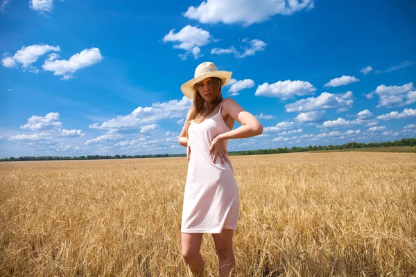 Menina loira jovem em vestido branco andando em um campo de trigo — Fotografia de Stock