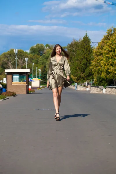 夏の木の上を歩く緑のドレスを着た若い美しい女性 — ストック写真