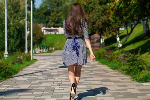 Junge schöne Frau in grauem Kleid, die auf der Sommerstraße spaziert — Stockfoto