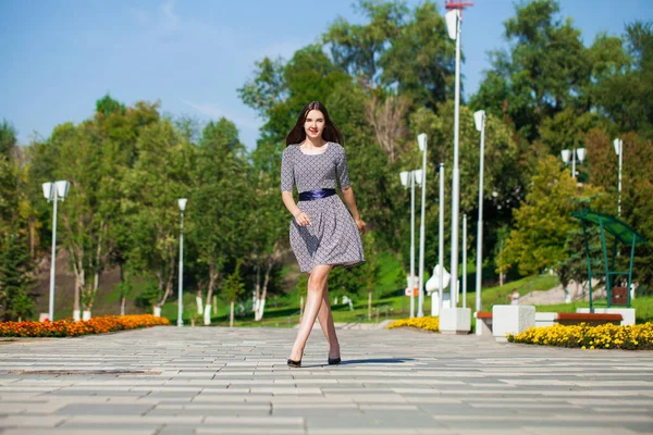 Junge schöne Frau in grauem Kleid, die auf der Sommerstraße spaziert — Stockfoto