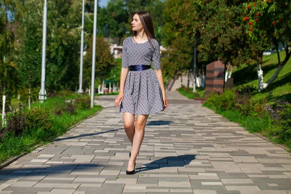 Junge schöne Frau in grauem Kleid, die auf der Sommerstraße spaziert — Stockfoto