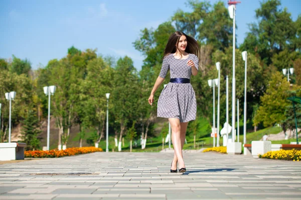 Νεαρή όμορφη γυναίκα με γκρίζο φόρεμα περπάτημα στο δρόμο του καλοκαιριού — Φωτογραφία Αρχείου