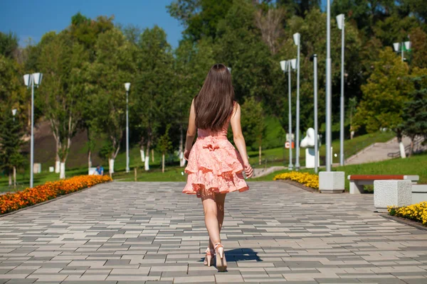 Молодая красивая женщина в розовом платье ходит по летней улице — стоковое фото