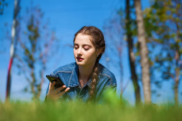 Mooie jonge brunette vrouw liggend op het groene gras — Stockfoto