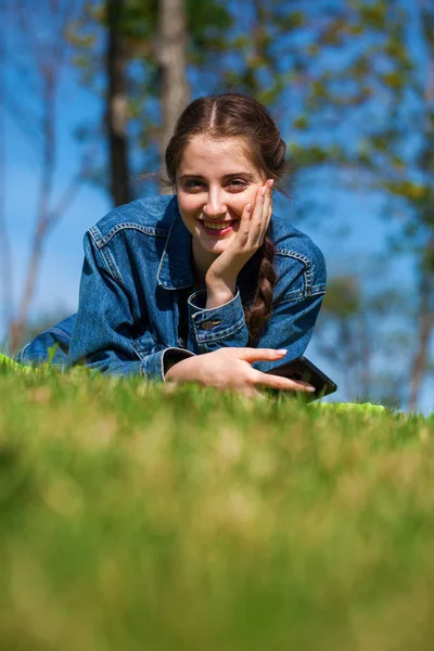 Krásná mladá brunetka ležící na zelené trávě — Stock fotografie