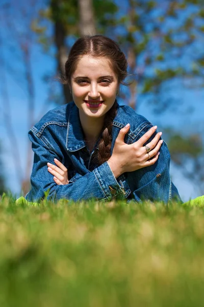 Beautiful young brunette woman lying on the green grass — Stock Photo, Image