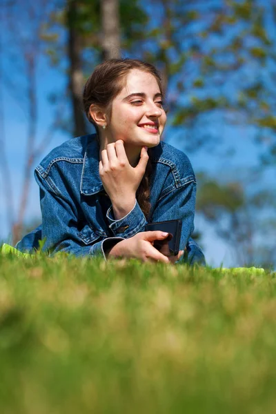 Schöne junge brünette Frau liegt auf dem grünen Gras — Stockfoto