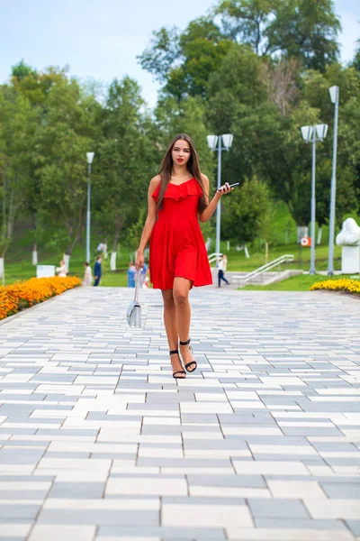 Jovem modelo bonito em vestido vermelho andando na rua de verão — Fotografia de Stock