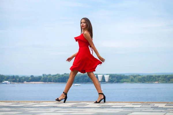 Junges schönes Model in rotem Kleid spaziert auf der Sommerstraße — Stockfoto