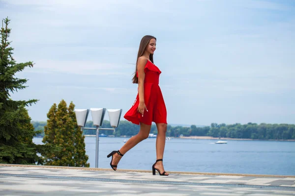 Jeune beau mannequin en robe rouge marchant dans la rue d'été — Photo