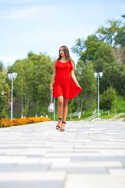 Yaz sokakta yürüyen kırmızı elbiseli genç güzel model — Stok fotoğraf