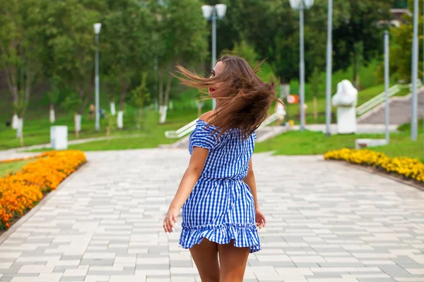 Back View ung brunett modell promenader i sommarpark, Utomhus — Stockfoto