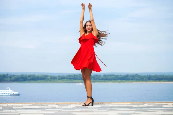 Jeune beau mannequin en robe rouge marchant dans la rue d'été — Photo