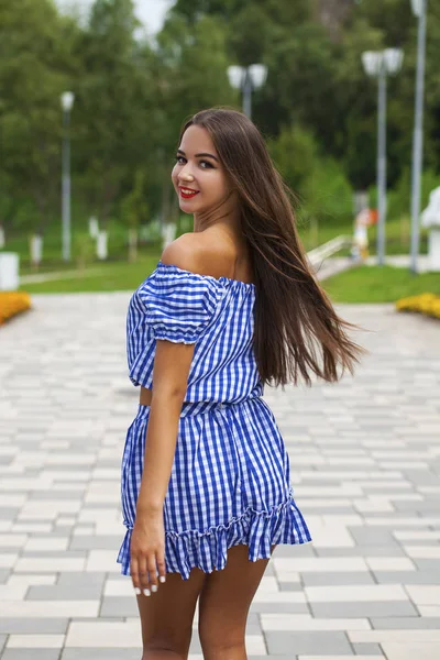 Молодая красивая женщина в темно-синем платье идет по летней улице — стоковое фото