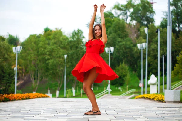 Jeune belle fille en robe rouge marchant dans la rue d'été — Photo