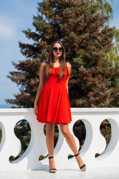 夏の通りに赤いドレスを着た若い美しい女性 — ストック写真