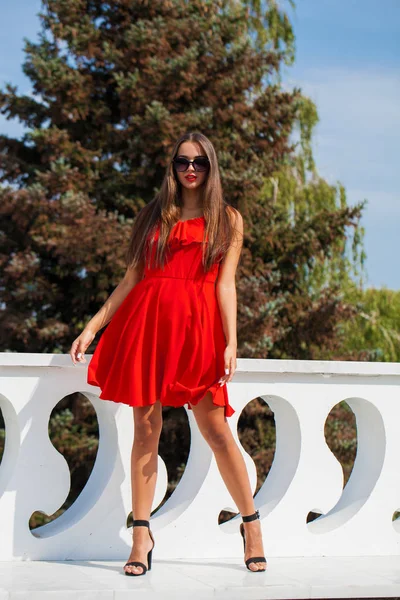 Молодая красивая женщина в красном платье на летней улице — стоковое фото