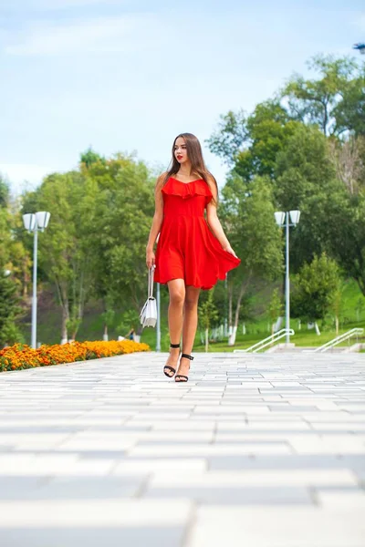 Jeune beau mannequin en robe rouge marchant dans la rue d'été — Photo