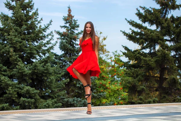 Jovem modelo bonito em vestido vermelho andando na rua de verão — Fotografia de Stock