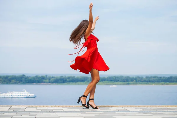 Mladá krásná žena v červených šatech v letní ulici — Stock fotografie