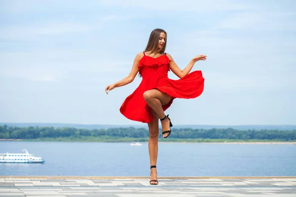 Jovem modelo bonito em vestido vermelho andando na rua de verão — Fotografia de Stock