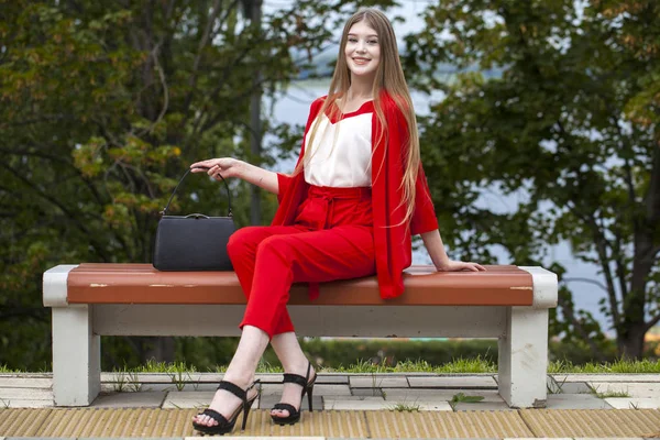 Молода красива жінка в червоному костюмі на літній вулиці — стокове фото
