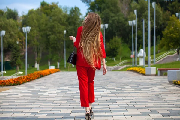 Молодая красивая женщина в красном костюме на летней улице — стоковое фото