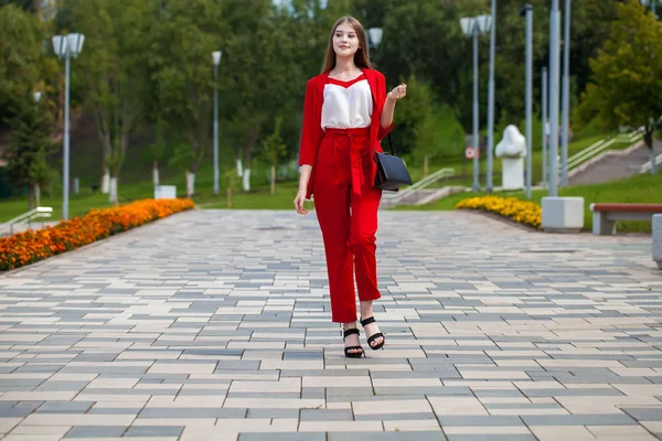 Mladá krásná žena v červeném obleku na letní ulici — Stock fotografie