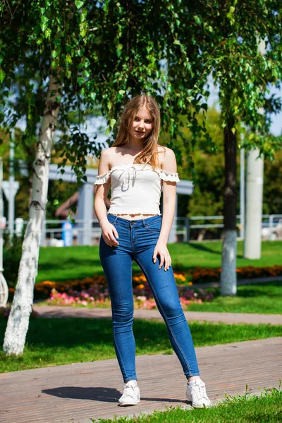 Jonge blonde zakenvrouw in blauwe jeans en wit overhemd — Stockfoto