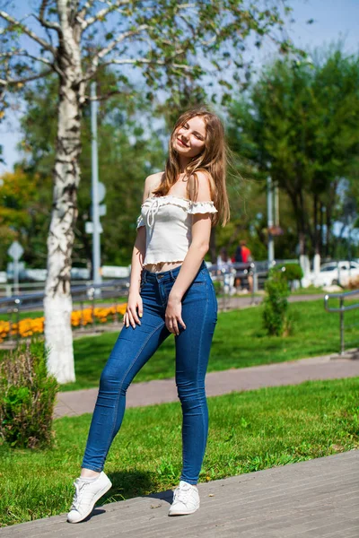 Молодая блондинка в синих джинсах и белой рубашке — стоковое фото