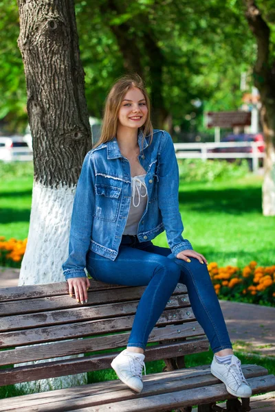 Mooi blond meisje in denim jasje en blauwe jeans — Stockfoto