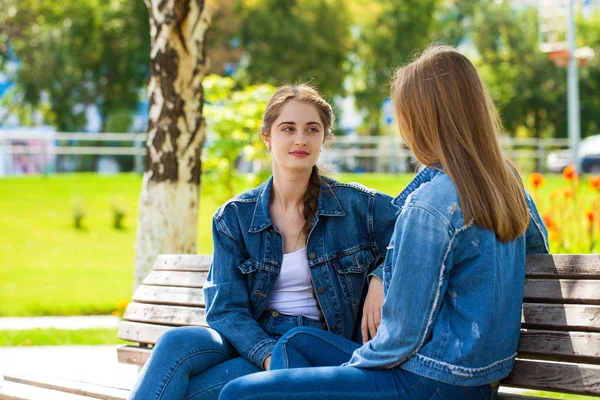 Dwie piękne dziewczyny mówią w parku siedzi na Ben — Zdjęcie stockowe