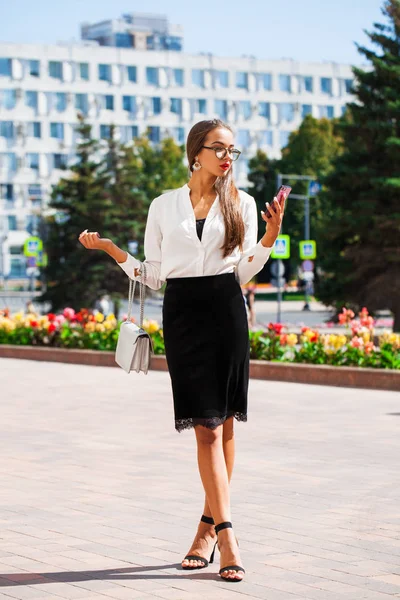 Young brunette woman reading a message on the phone — Stock Photo, Image