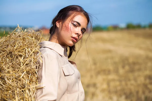 Menina bonita em um vestido bege posando em um fundo de haysta — Fotografia de Stock