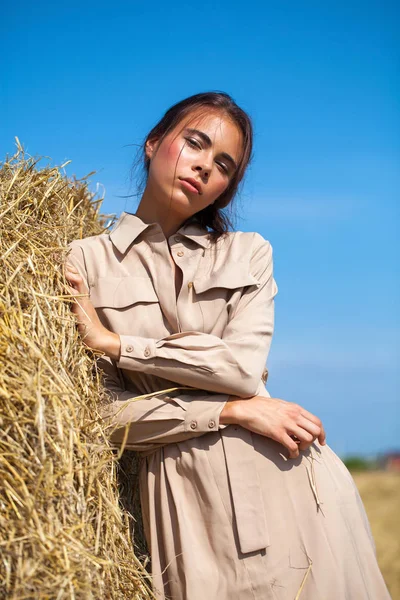 Menina bonita em um vestido bege posando em um fundo de haysta — Fotografia de Stock