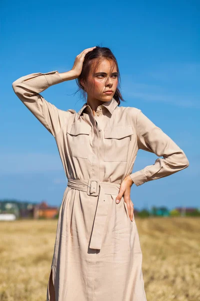 Fiatal, gyönyörű barna modell egy bézs színű ruha pózol ellen — Stock Fotó